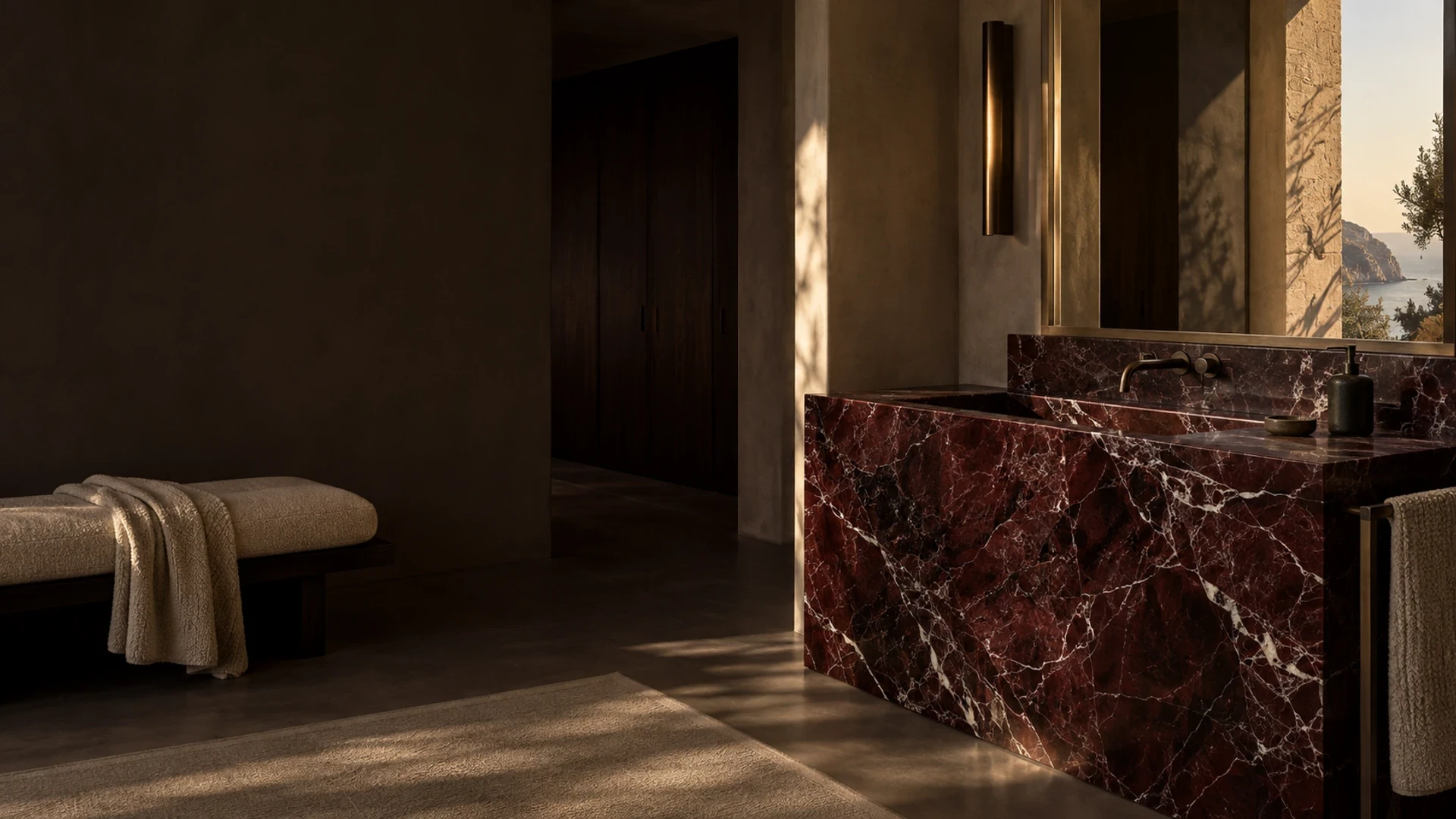Vasque monolithique en marbre Rosso Levanto rouge bordeaux dans une salle de bain aux enduits minéraux et au noyer sombre.